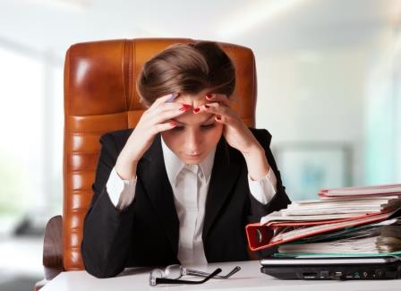 Tensed young business woman holding her head while at work