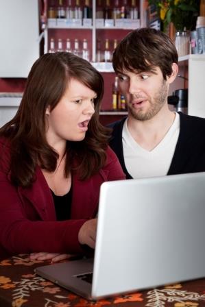 Woman and man staring in disbelief at a computer laptop
