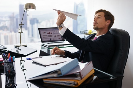 Bored White Collar Worker Throwing Paper Airplane In Office