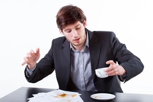 Young businessman spills coffee for documents