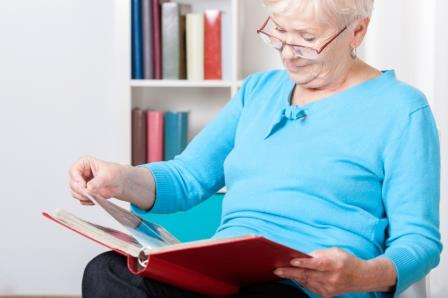 Elderly woman watching photos in family photo album